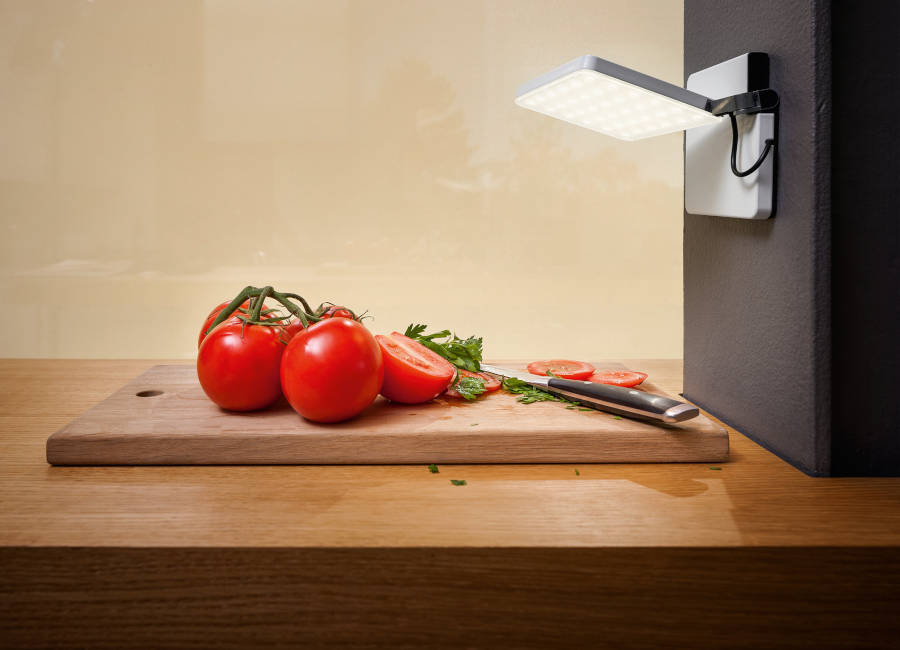 Ein Schneidebrett, auf dem Tomaten, eine Möhre und ein Messer liegen, wird von einer an der Wand befestigten Nimbus Roxxane Fly beleuchtet. (Foto: Uwe Ditz)