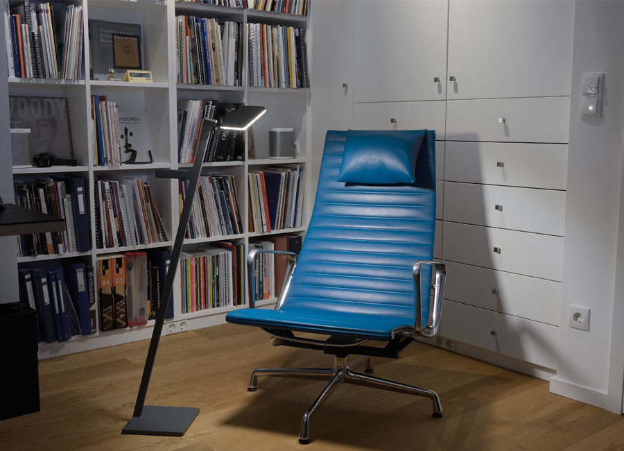 Eine Leseecke mit einer modernen, kabellosen Standleuchte neben einem blauen Drehstuhl. (Foto: Prediger Lichtberater)