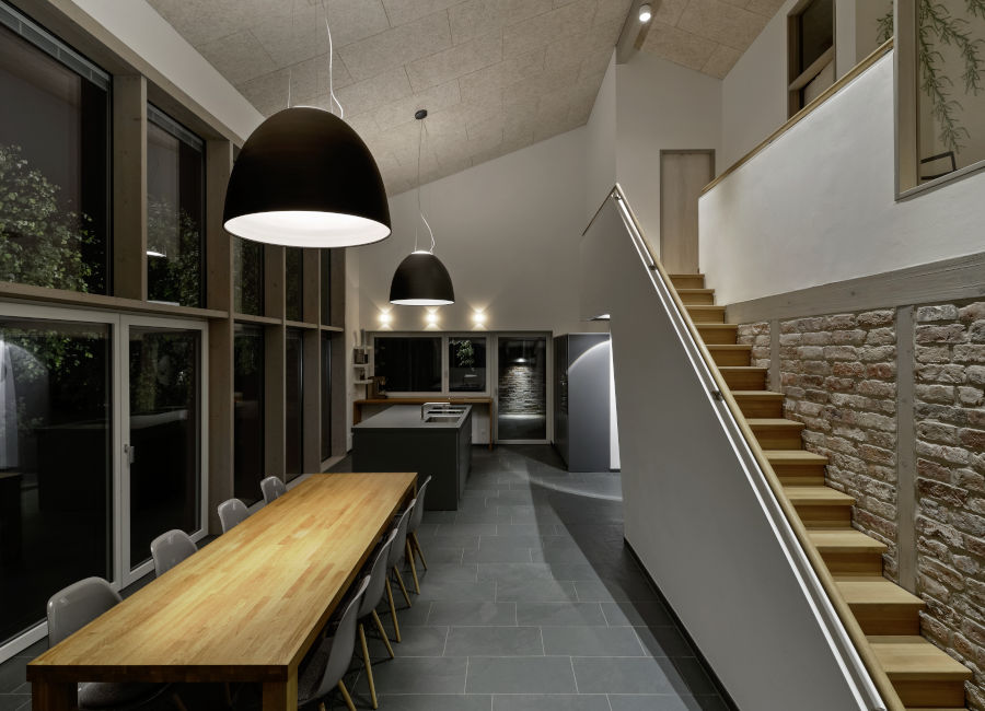 Küche und Esszimmer mit Dachschräge in einer Ferienwohnung in Schleswig-Holstein. Die Beleuchtung wird über zwei große Pendelleuchten gelöst.