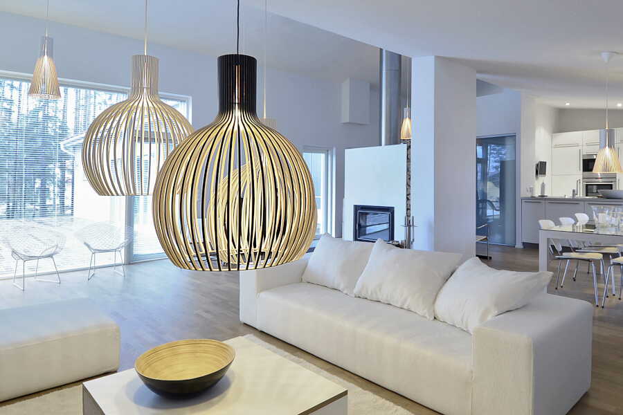 Eine Octo 4240 Pendelleuchte hängt über einem Wohnzimmertisch, im Hintergrund sind eine Couch und ein Esstisch zu sehen. (Foto: Secto Design)