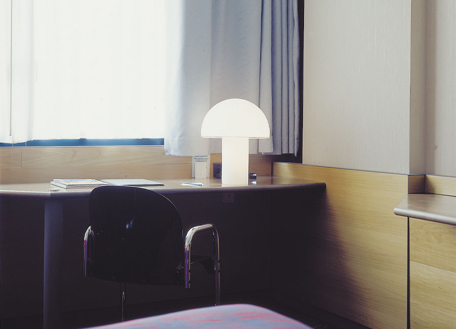 Die an einen Pilz erinnernde Tischleuchte Onfale Tavolo steht auf einem Schreibtisch vor einem Fenster. (Foto: Artemide)
