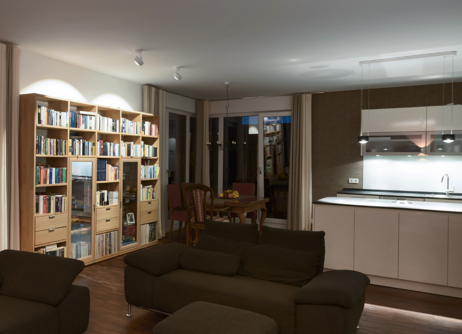 Eine Penthousewohnung im Süden Berlins: Das Bücherregal links wird von zwei Deckenspots in Szene gesetzt, die Küche rechts von zwei Pendelleuchten in gleicher Bauart. (Foto: Prediger Lichtberater)