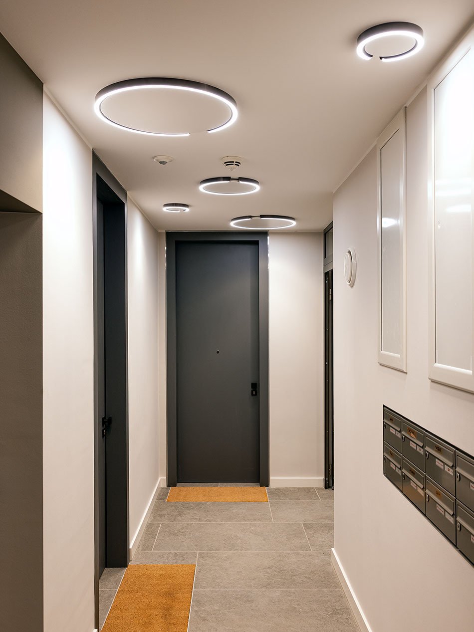 Moderner Hausflur mit mehreren Mito Soffitto Deckenleuchten in unterschiedlichen Größen von Occhio.