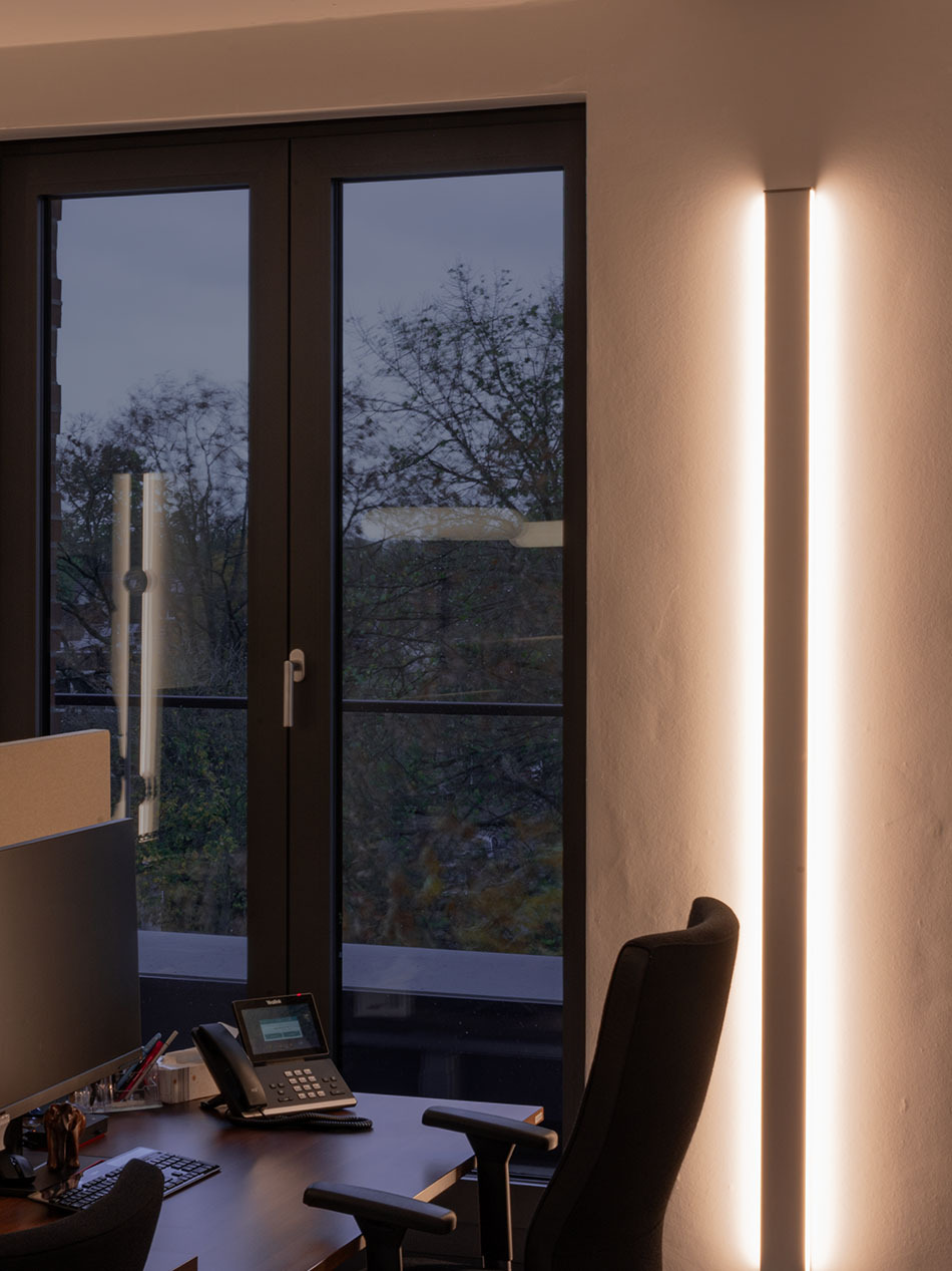 Vertikale LED-Wandprofile von Sigor sorgen für die Allgemeinbeleuchtung in einem Gemeinschaftsbüro.