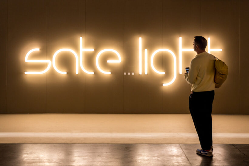 Ein Besucher steht vor dem beleuchteten Logo der Ausstellung "Sate...light", die 2023 im Rahmen der Euroluce stattgefunden hat.