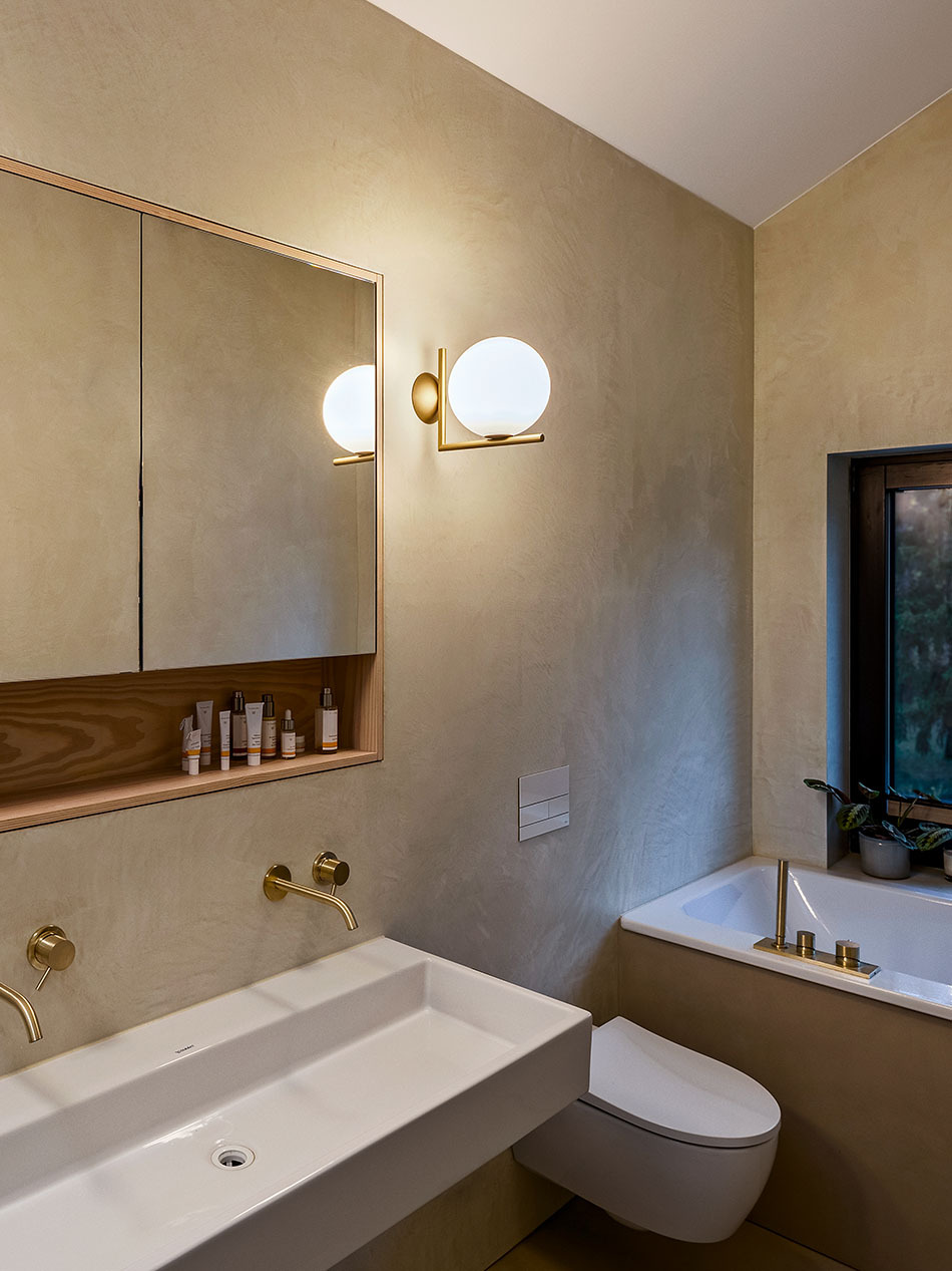 Modernes Badezimmer mit einer IC Lights Wandleuchte von Flos, die neben einem großen Spiegelschrank hängt.