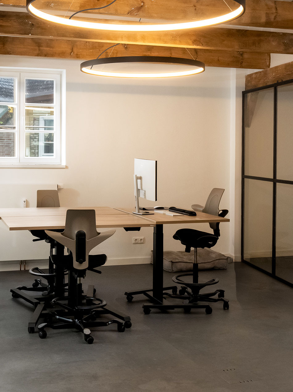 Mondernes Büro mit zwei schwarzen Superloop Pendelleuchten von Artemide, die mehrere Arbeitsplätze beleuchten