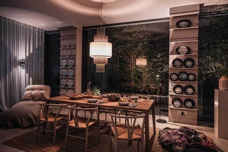 Modernes Esszimmer mit gedecktem Esstisch unter einer grünen Pendelleuchte Plivello von Le Klint. Im Hintergrund stehen zwei schwarze s.200 Stehleuchten von prediger.select. Der Raum ist stilvoll und modern eingerichtet.