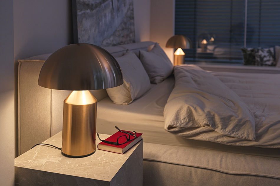 Schlafzimmer mit zwei Atollo Tischleuchten von Oluce in Metall Gold, die als Nachttischleuchten dienen und neben dem Bett stehen. Das Schlafzimmer ist gemütlich mit einem Kunstwerk über dem Bett
