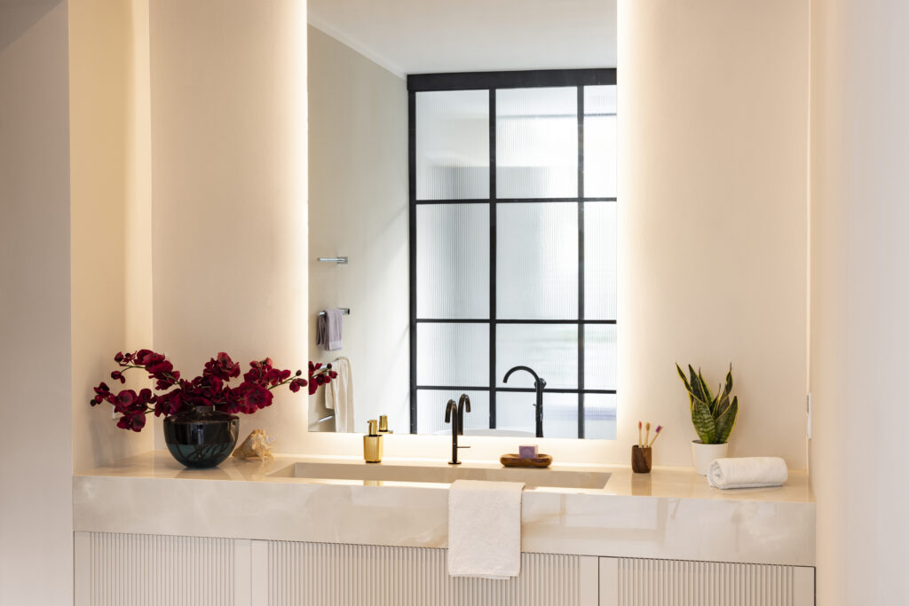 Modernes Badezimmer mit minimalistischer Einrichtung, schwarzem Wasserhahn und dezenter Beleuchtung.