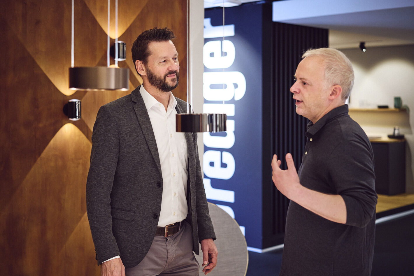 Ein Berater von Prediger Lichtberater unterhält sich mit einem männlichen Kunden im Showroom vor einer Wand mit Beleuchtung. (Foto: Johannes Arlt)