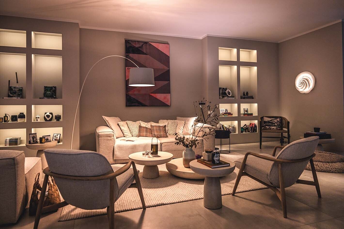 Modernes Wohnzimmer mit hellen Möbelstücken und einer Twiggy Terra Stehleuchte von Foscarini. Außerdem ist eine Swirl Wandleuchte von Le Klint zu sehen. Die Schränke werden von p.143 Lichtleisten von prediger.base beleuchtet.