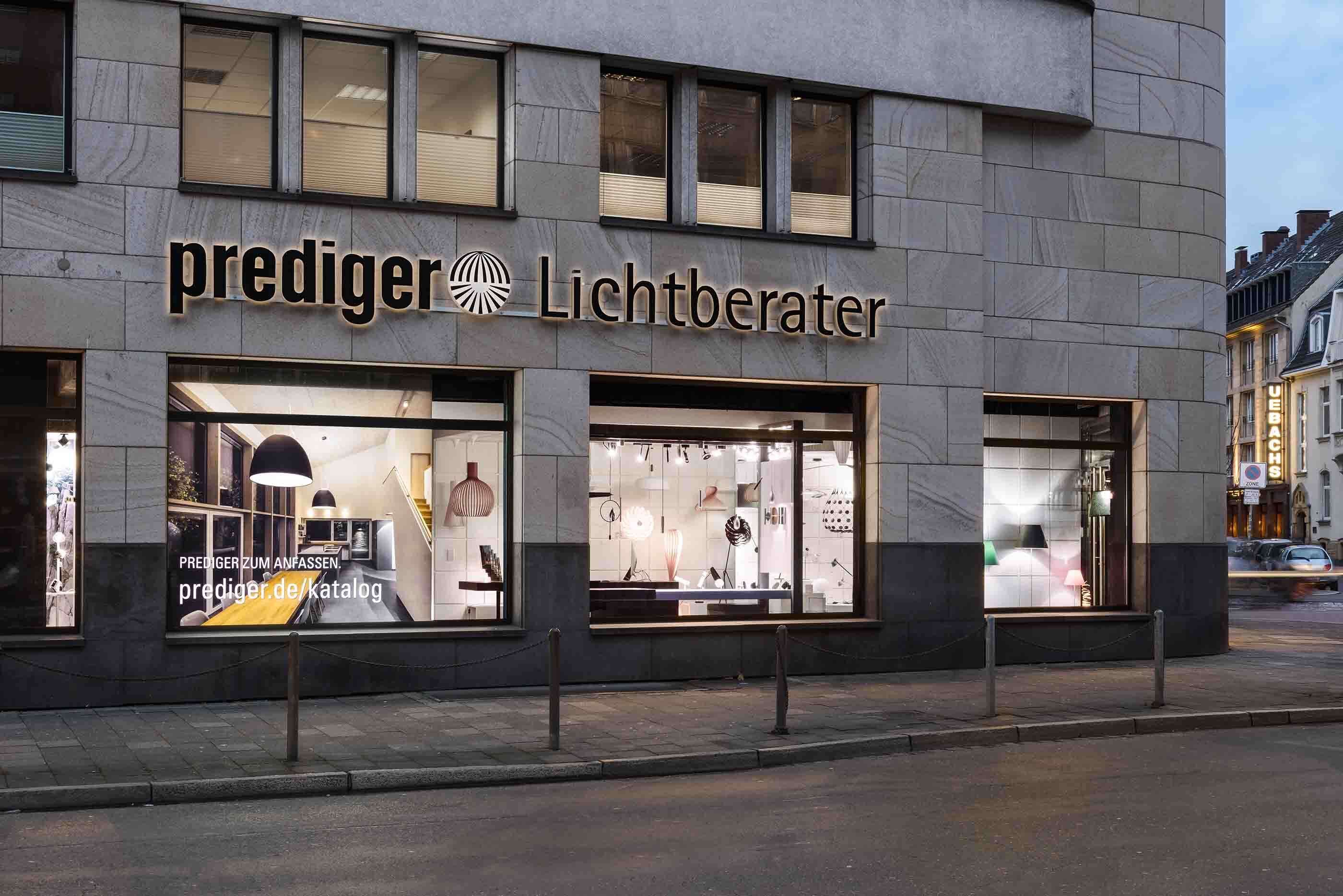 Außenaufnahme des Düsseldorfer Showrooms. Durch das Schaufenster kann man die Ladenfläche sehen. Der Showroom wird durch unterschiedliche Leuchten verschiedener