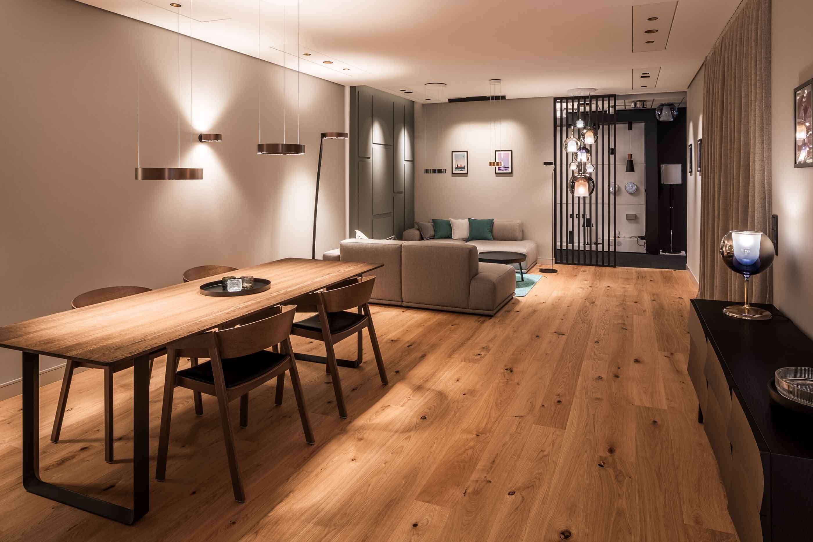 Ein Blick in den Lightcase im Showroom München von Prediger Lichtberater. Vorne links ist ein Esstisch, rechts ein Sideboard zu sehen, im Hintergrund links ein Wohnzimmer mit Couch und Sesseln. (Foto: Jonathan Palanco)