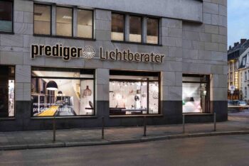 Außenaufnahme des Düsseldorfer Showrooms. Durch das Schaufenster kann man die Ladenfläche sehen. Der Showroom wird durch unterschiedliche Leuchten verschiedener