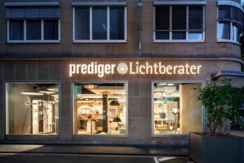 Außenaufnahme bei Abenddämmerung_ Der Showroom Köln wird durch unterschiedliche Leuchten im Innenbereich beleuchtet.