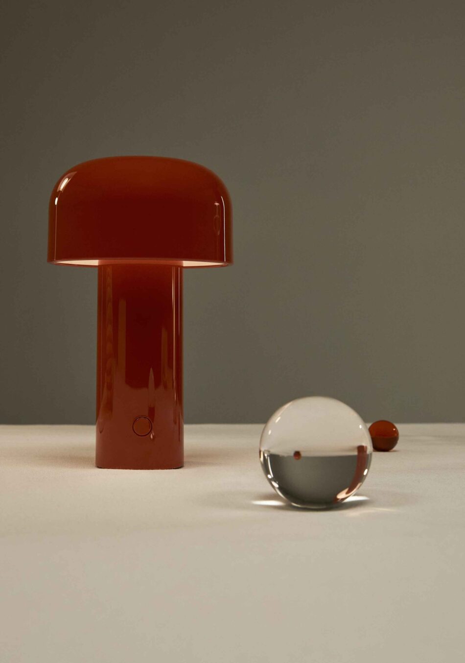 Esstisch mit roter Akku-Tischleuchte von Flos neben Dekoelementen. (Foto: Flos)