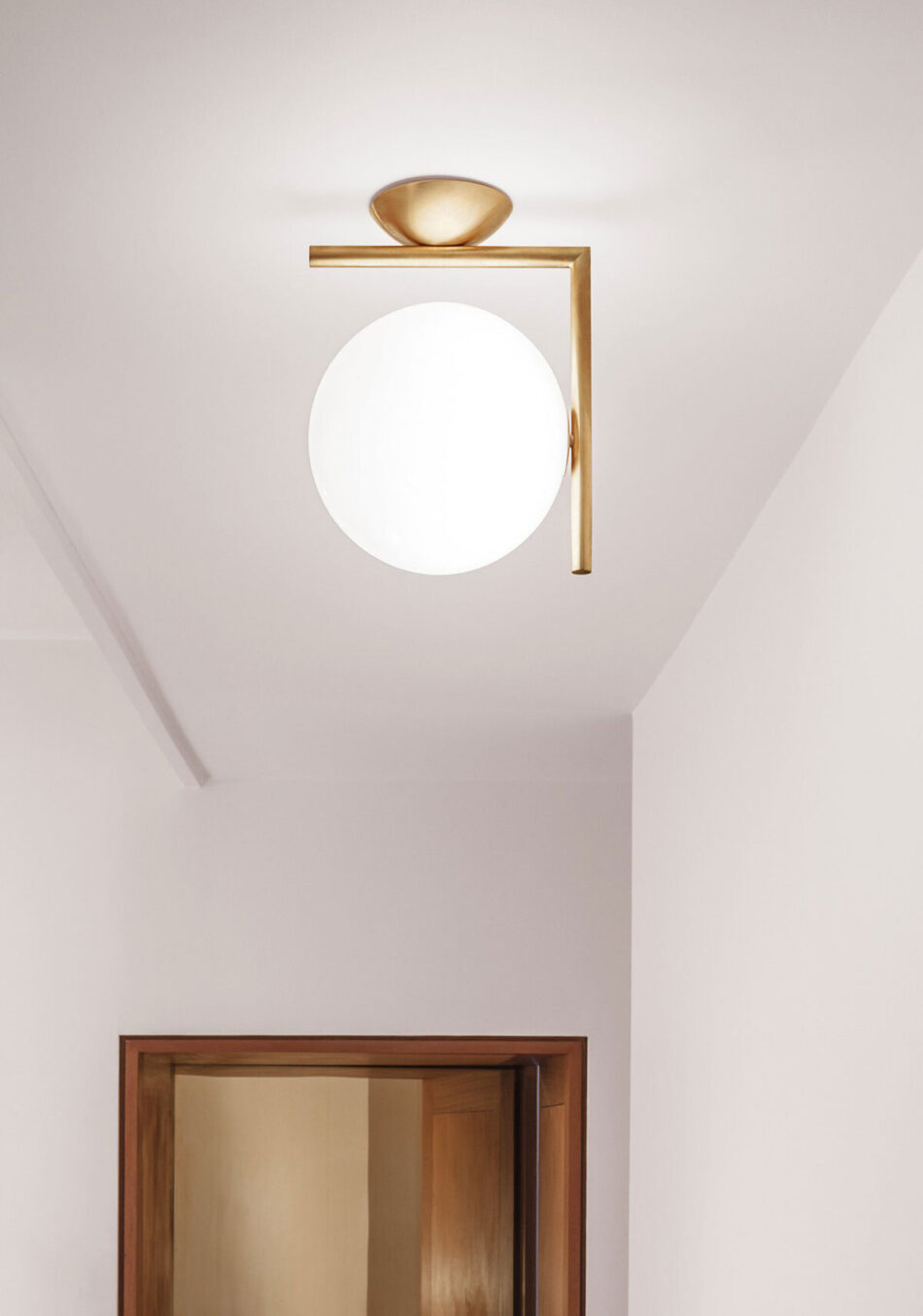 Ein Flur, beleuchtet von der modernen IC Lights Deckenleuchte von Flos in elegantem Gold mit kugelförmigem Design. (Bild: Flos)