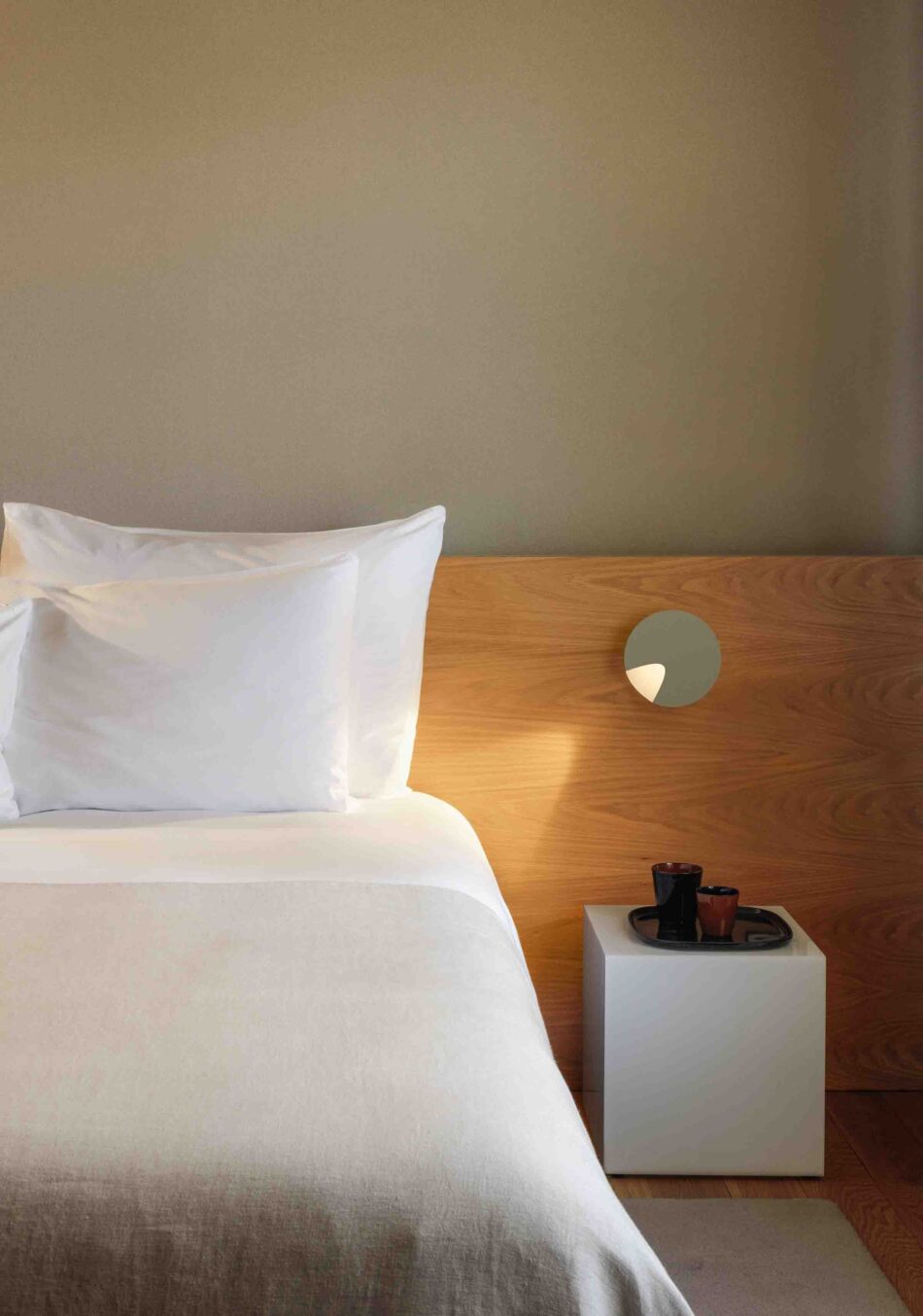 Modernes Schlafzimmer mit einer grünen Dots Wandleuchte von Vibia, die als Nachttischleuchte dient und für eine gezielte Akzentbeleuchtung sorgt. (Foto: Vibia)