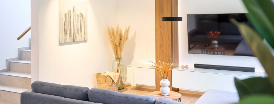 Modernes helles Wohnzimmer mit einer schwarzen c.Space Pendelleuchte von CHRISTOPH, die über zwei kleinen Beistelltischen hängt