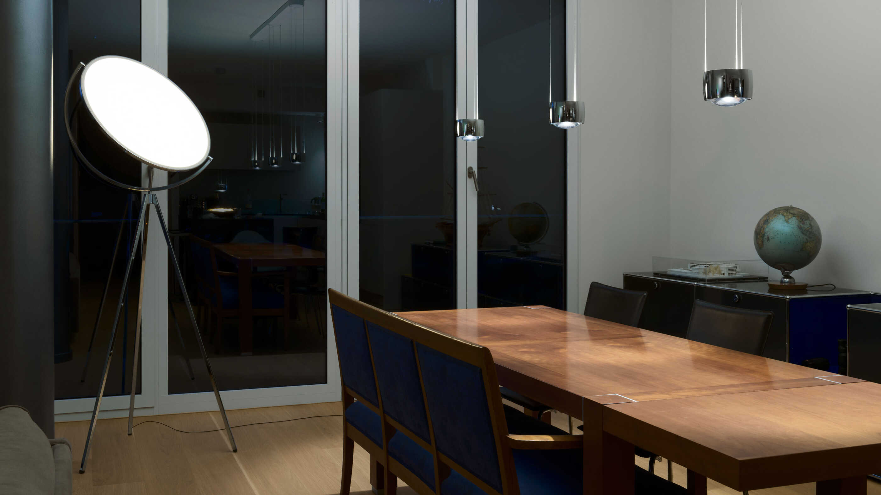Ein Esstisch wird von drei Pendelleuchten direkt beleuchtet. Eine Standleuchte trägt mit diffusem Licht zum Raumlicht bei.