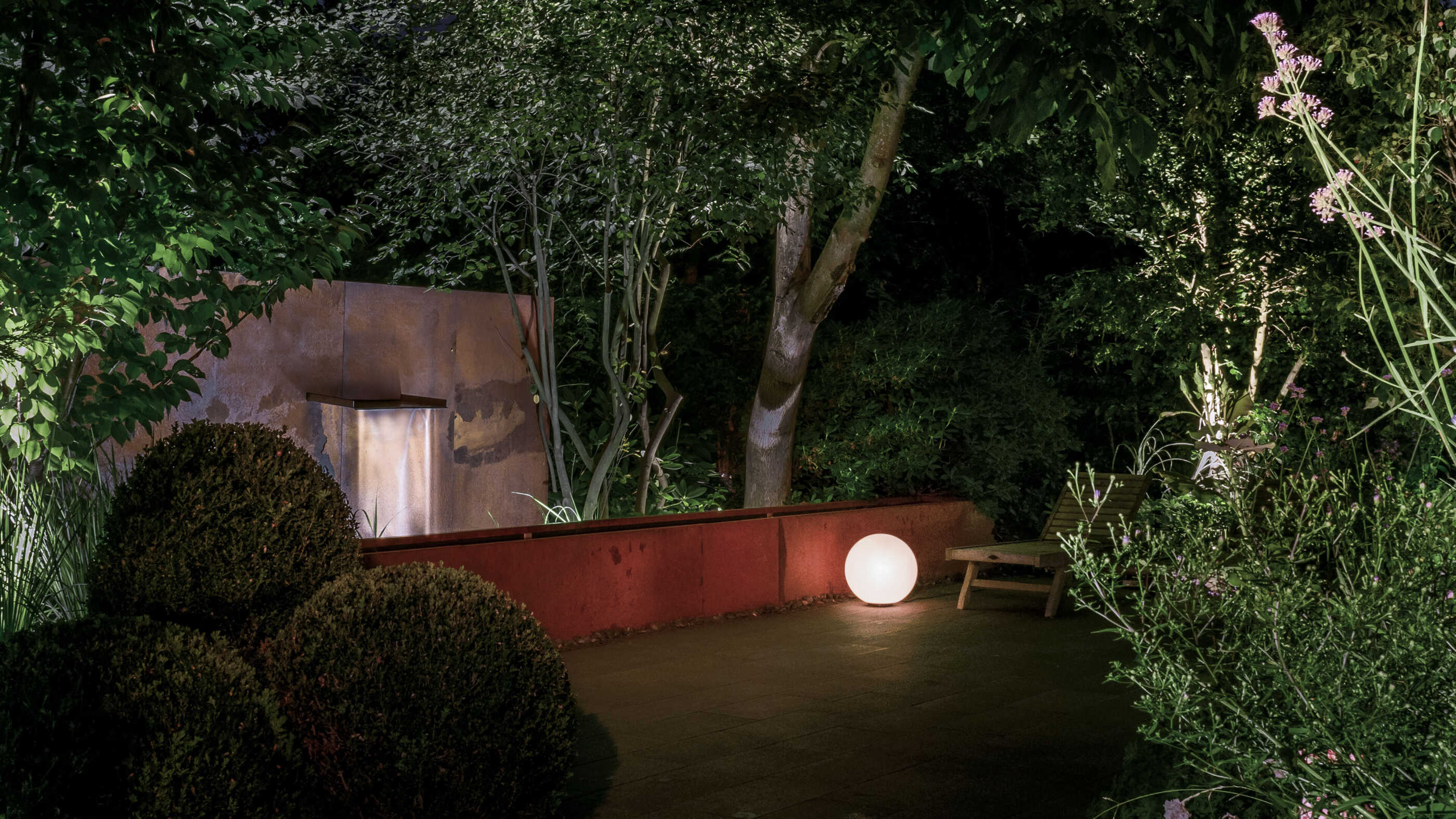 Ein kleines Wasserspiel neben einer Terrasse wird von einer diffus-allgemein strahlenden Kugelleuchte angeleuchtet. (Foto: Prediger Lichtberater)