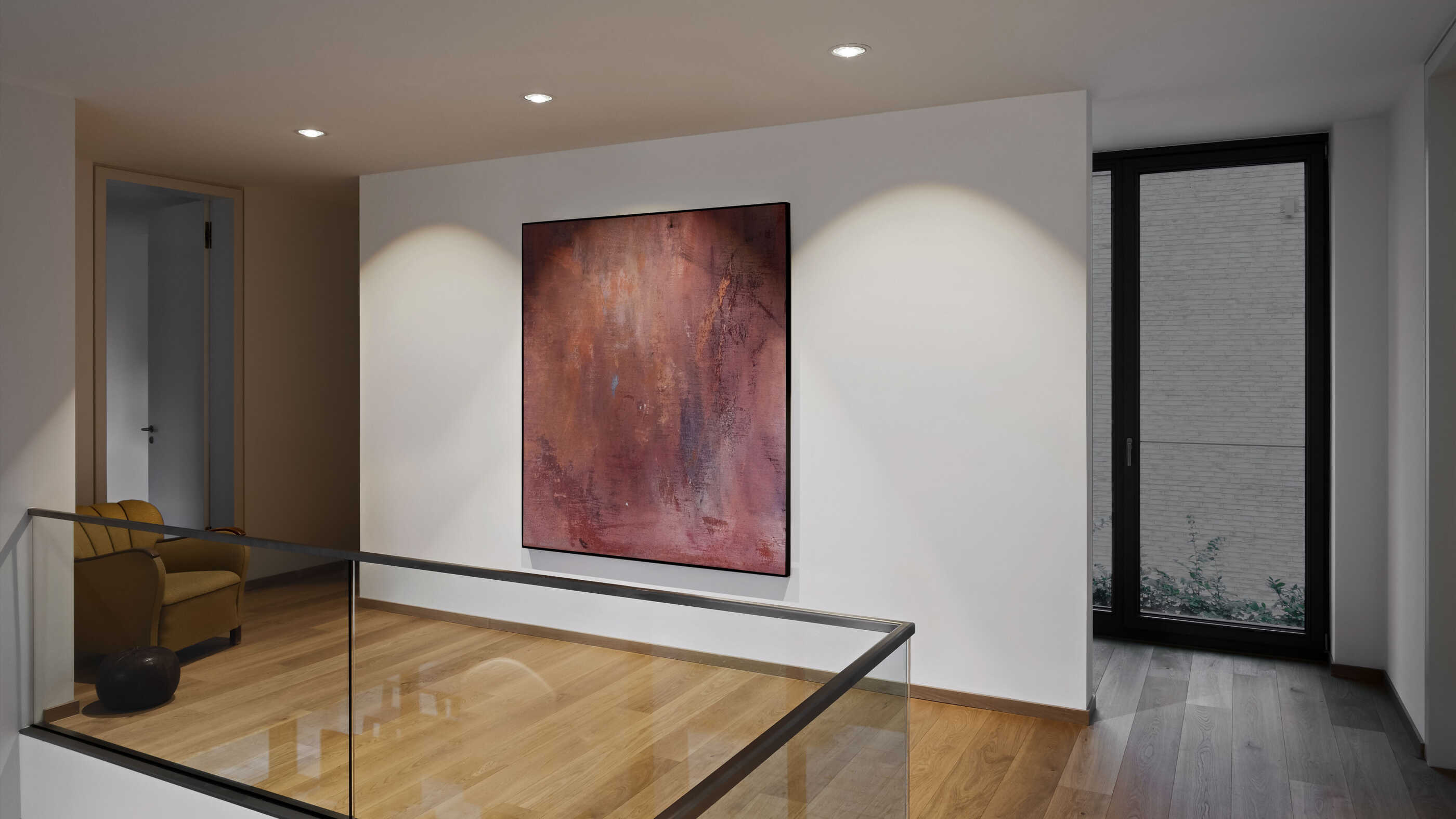 Eine Galerie in einem Flur: Drei Downlights beleuchten eine Wand mit einem großformatigen Bild. (Foto: Prediger Lichtberater)