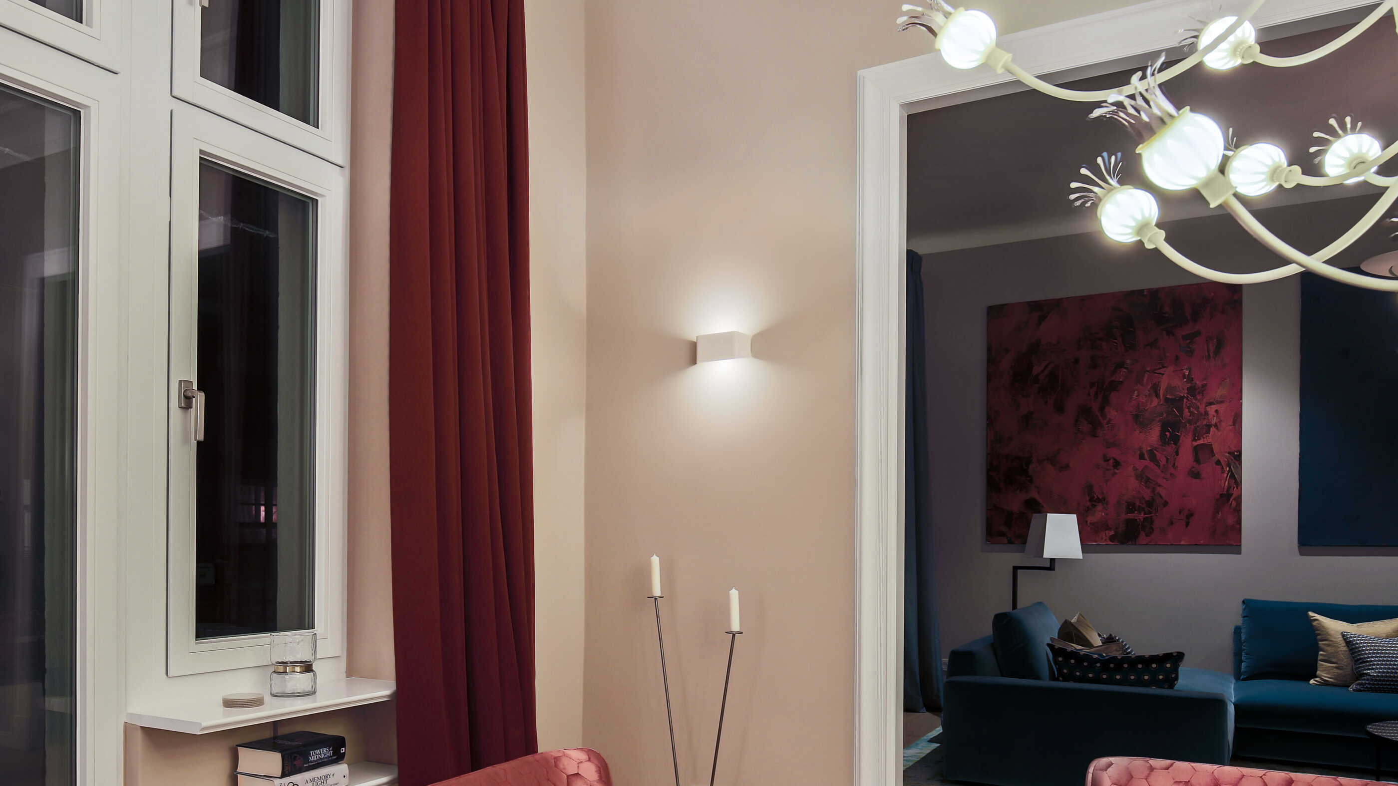 Detailansicht im Esszimmer einer Berliner Altbauwohnung: Eine Wandleuchte neben einem Durchgang setzt einen Lichtakzent, im Hintergrund rechts ist das Wohnzimmer zu sehen. (Foto: Prediger Lichtberater)