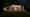 Ein Ferienhaus in Schleswig-Holstein bei Nacht aus leicht schräger Perspektive: Die zweigeschossige Fensterfront erstreckt sich fast über die gesamte Breite des Hauses und ist hell erleuchtet, Wandleuchten links und rechts rahmen das Fenster ein. (Foto: Prediger Lichtberater) imageThumbnailAlt