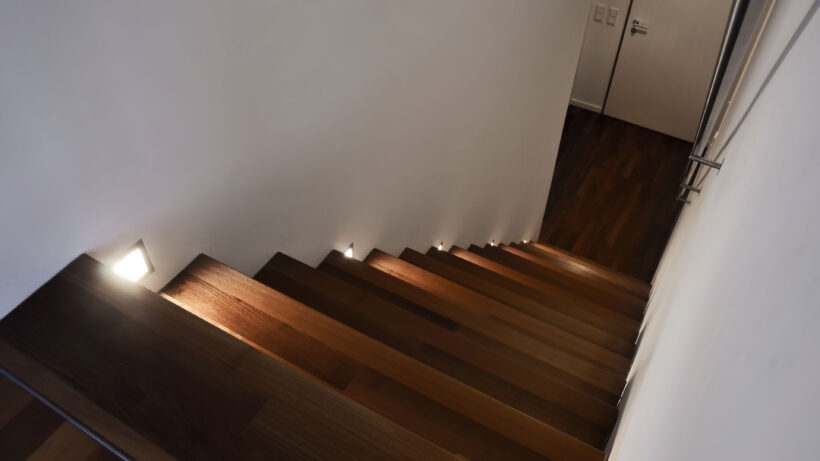 Die Treppe zu einem Penthouse in einem Hamburer Szeneviertel, Blick von oben nach unten. Jede dritte Treppenstufe wird von einer kleinen Wandleuchte beleuchtet. (Foto: Prediger Lichtberater)