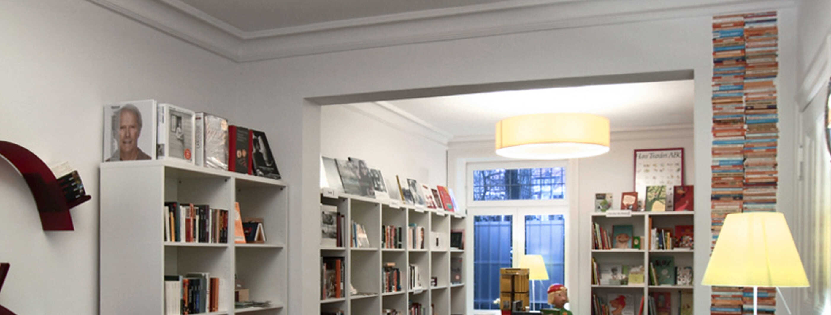 Die Geschäftsräume einer Buchhandlung: Eine Deckenleuchte, eine Standleuchte und eine Tischleuchte sorgen für ein gleichmäßiges Licht zwischen den Bücherregalen. (Foto: Prediger Lichtberater)