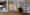 Das Wohnzimmer in einer Wohnung in Hamburg Altona: Ein Bücherregal nimmt die gesamte rechte Seite ein, davor stehen ein Sessel, eine Leseleuchte und ein kleiner Tisch. Links ist eine offene Küche zu sehen. (Foto: Prediger Lichtberater) imageThumbnailAlt